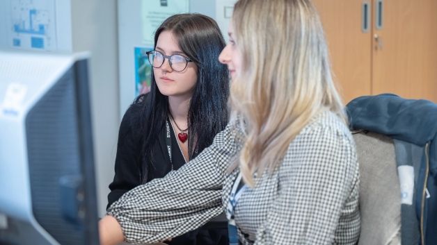 teacher and student looking at a computer. apply for college