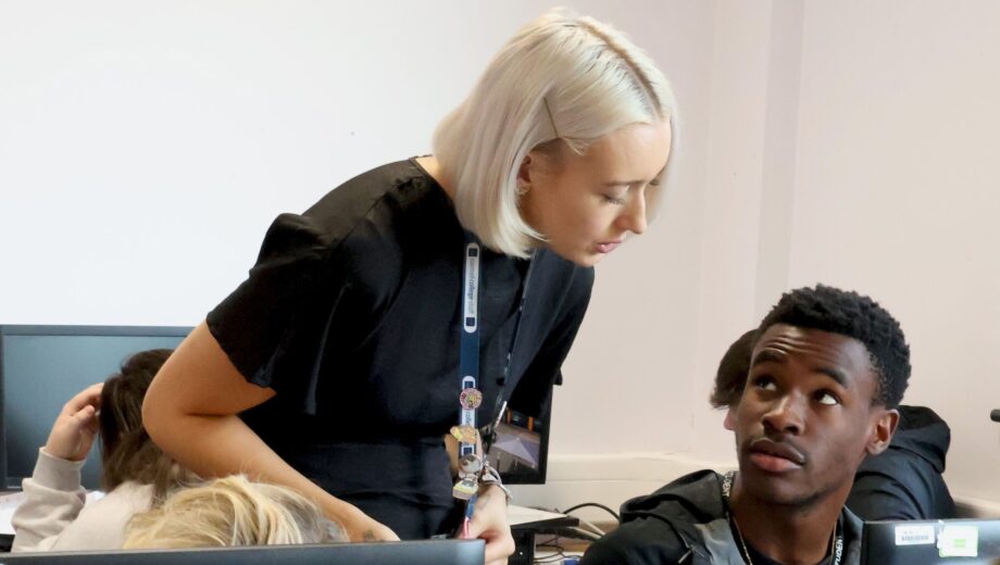 female teacher with blond hair talking to a student in class giving support