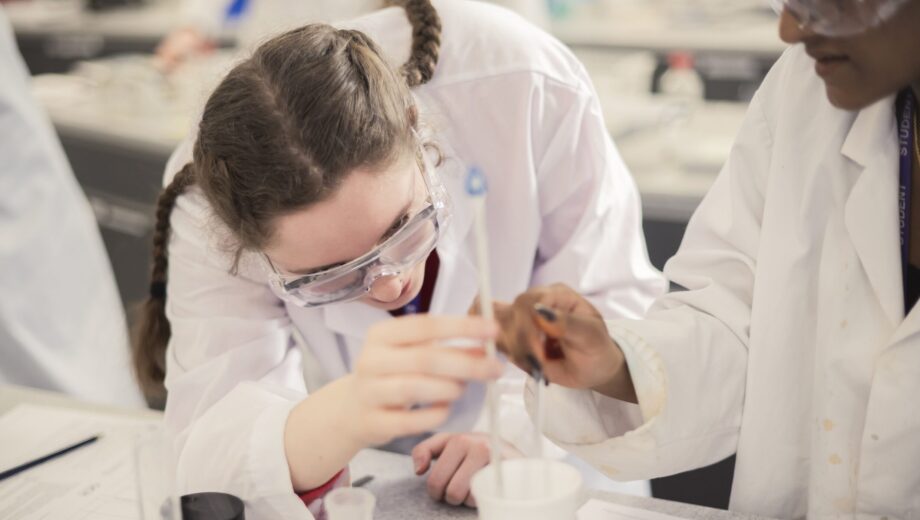 a student completing a experiment with lab coat and PPE on