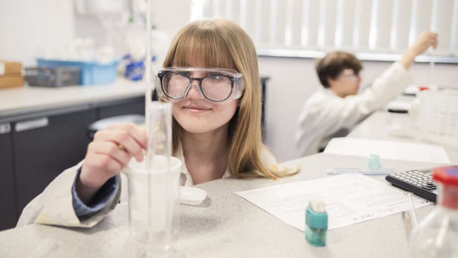a student completing a experiment, with a lab coat and PPE on