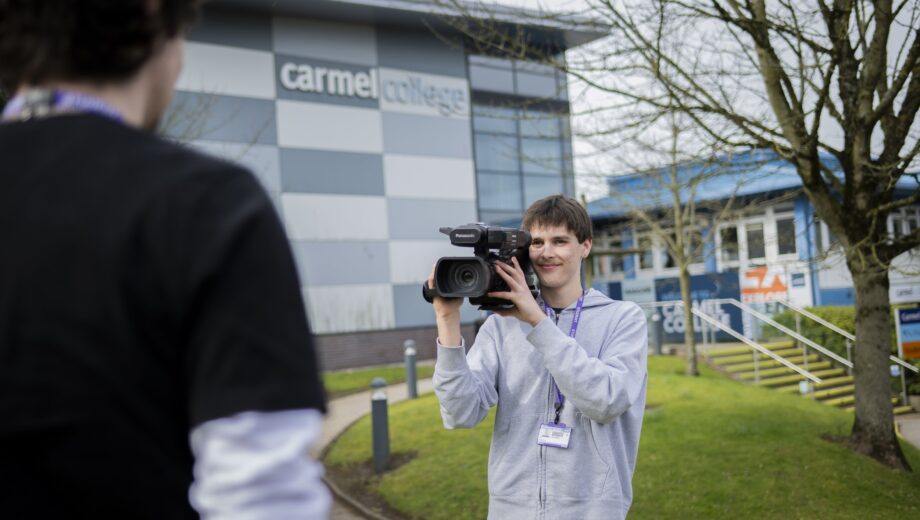 Student stood at the front of Carmel College with a video camera