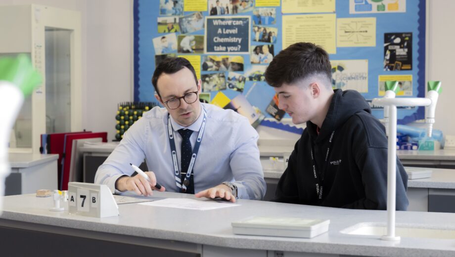 Male teacher and student sat looking at work at a desk