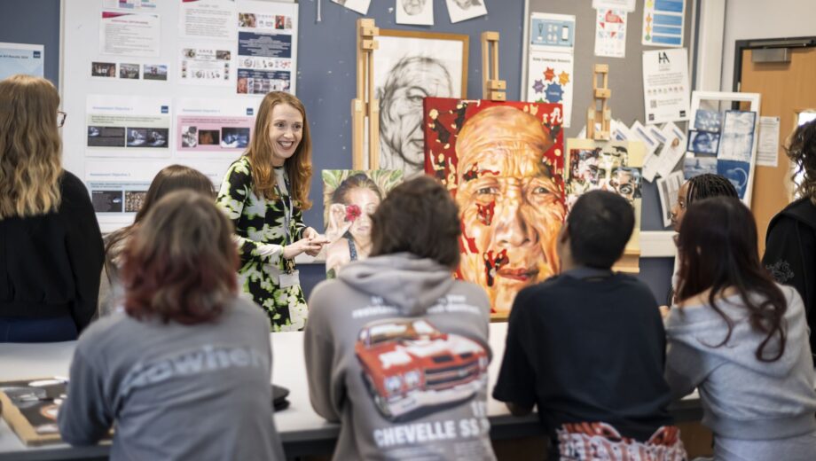 Fine Art Teacher stood at the front of her classroom teaching students