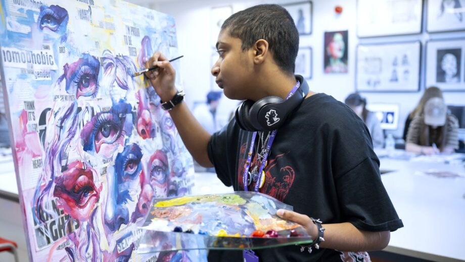 Student painting on a canvas using blues and purple paints