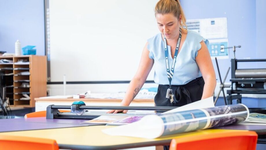 Female cutting paper using guillotine. apply for college near me