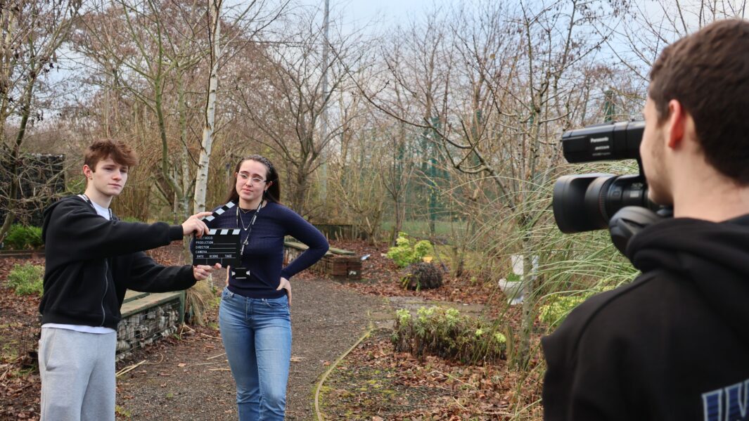 Photo of male and female students using film equipment outside