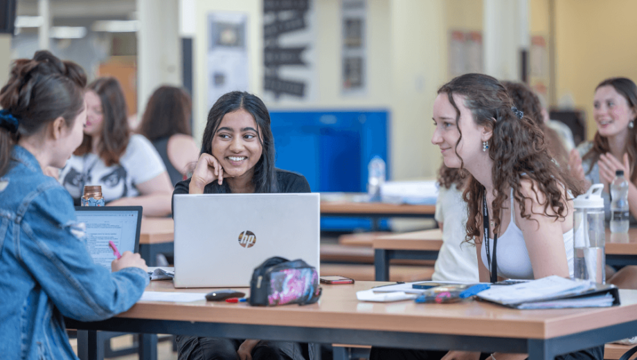 Three female students sat at a table talking