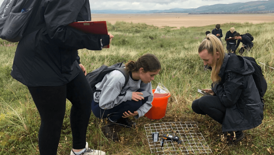 Two students completing fieldwork on a beach