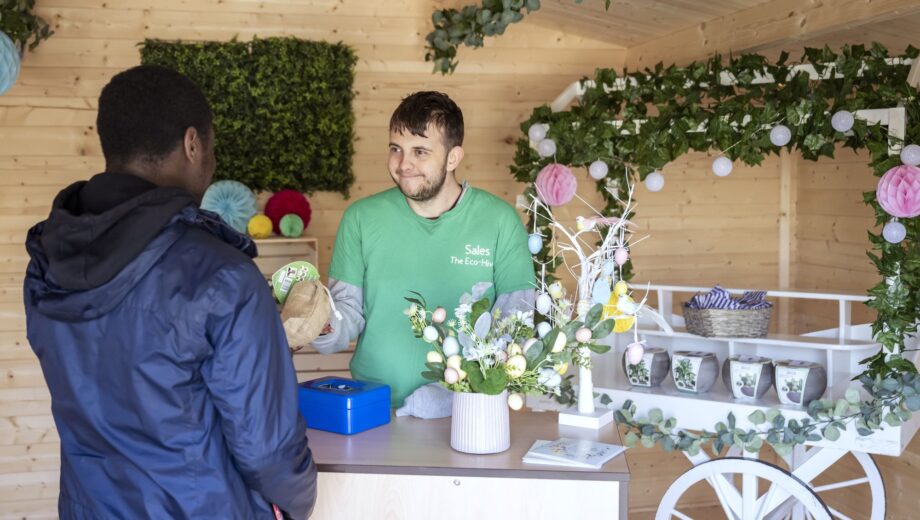 Male student stood with sweets cart serving another student
