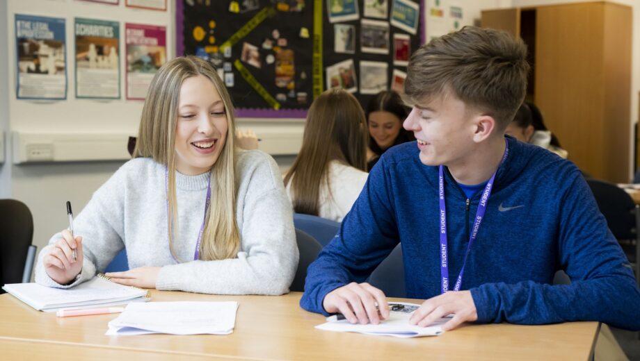 Boy and girl sat at a desk in a clssroom