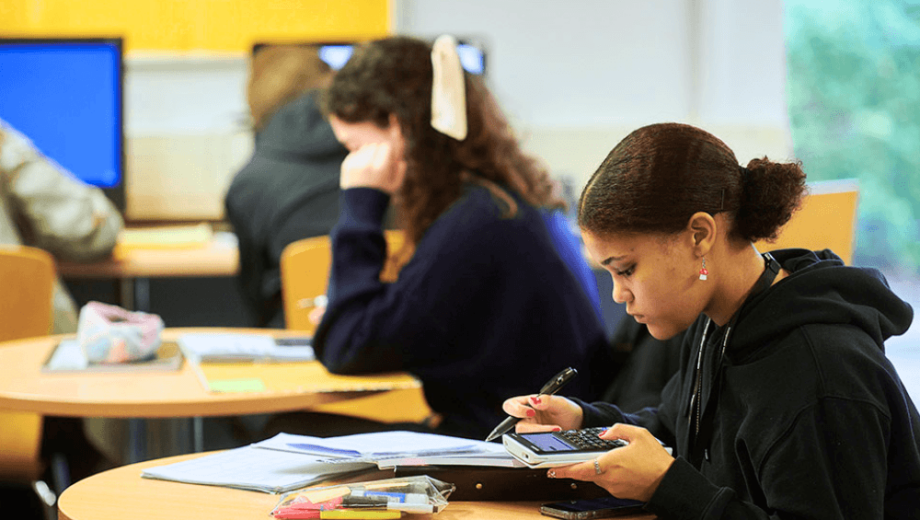 Girl sat in library using a calculator