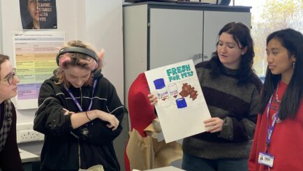 Group of students in the Art classroom holding up artwork