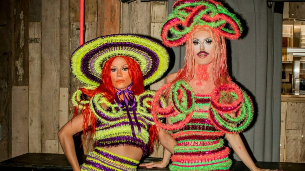 two models posing in multicoloured striped dresses and hats