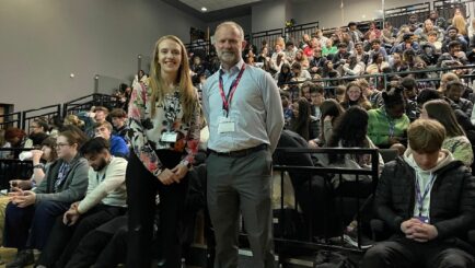 Theatre full of students and Liz Walls stood at the front with Dr Dominic Johnson