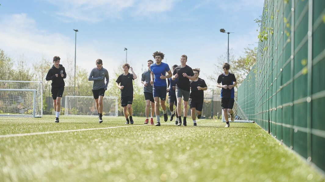 Group of male footballers running along on the astro pitch at Carmel College