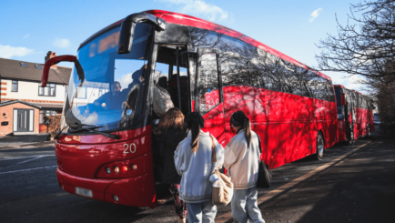Photo of the red St Gregory's bus with students getting on board outside Carmel