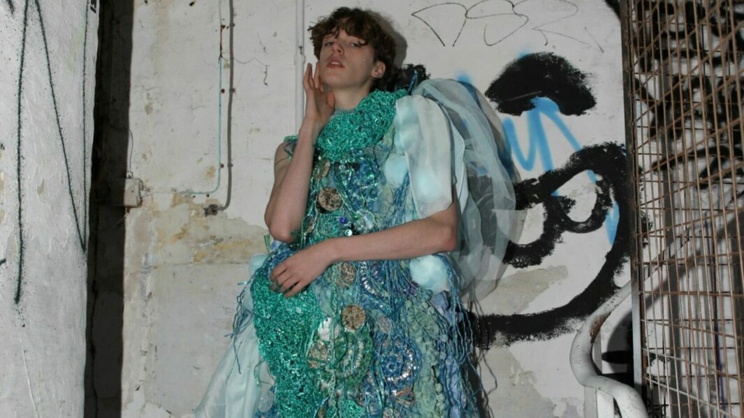 Model posing in stair well in blue textile dress