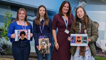 College Principal Janet Gater with three female students holding Black History Month winning entries