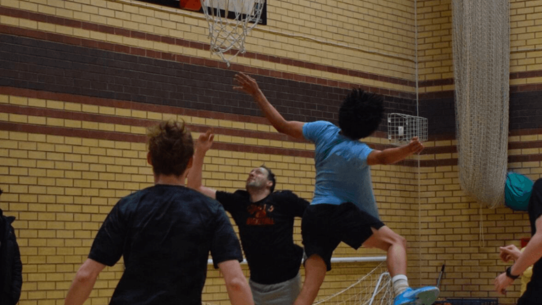 Students and staff in basketball match