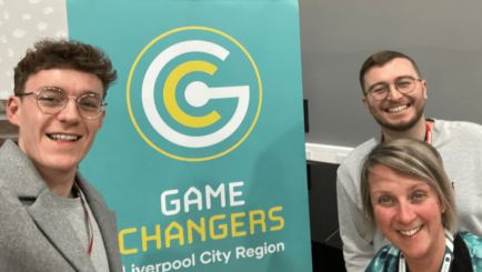 Two games developers pose with Carmel College member of staff