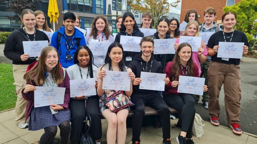 Group of students in the courtyard holding up certificates