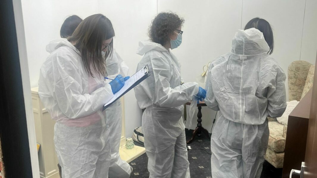 A group of students in bunny suits collecting evidence using clipboards