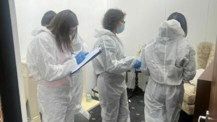 A group of students in bunny suits collecting evidence using clipboards