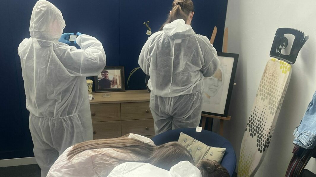 Two students at a CSI bunny suits collecting evidence