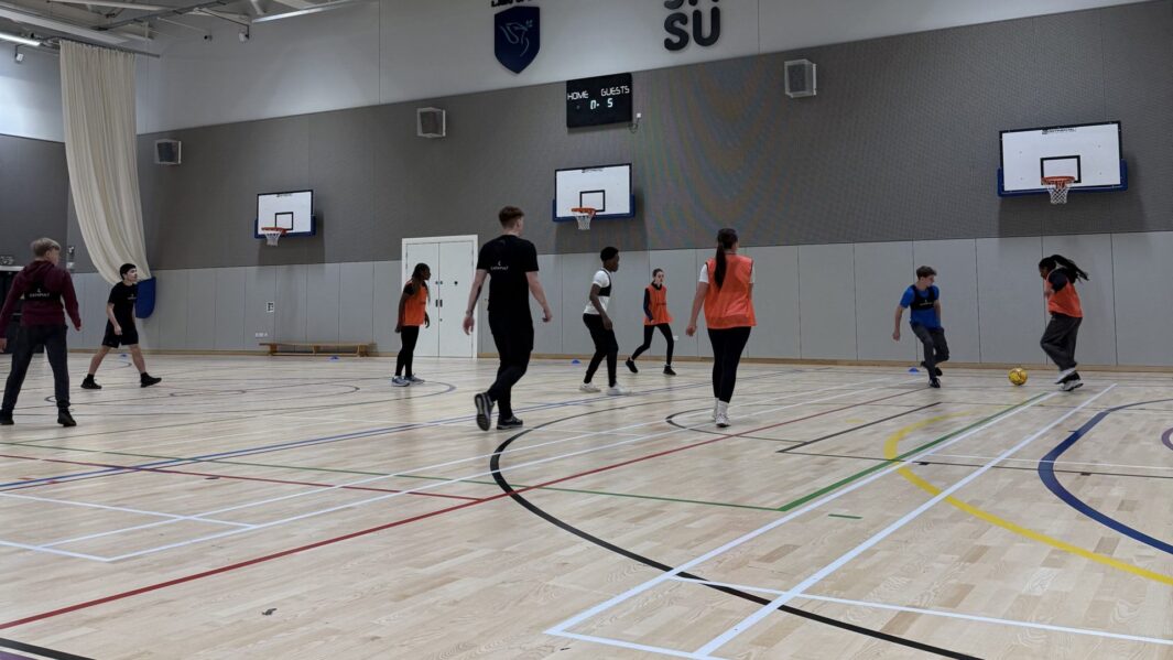 Students playing sport in a sports hall