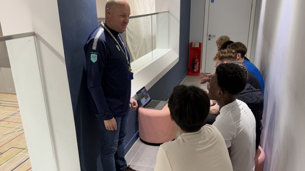 Students sat on stools talking to a staff member at LJMU