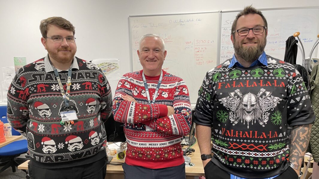 Three IT members of staff wearing Xmas jumpers