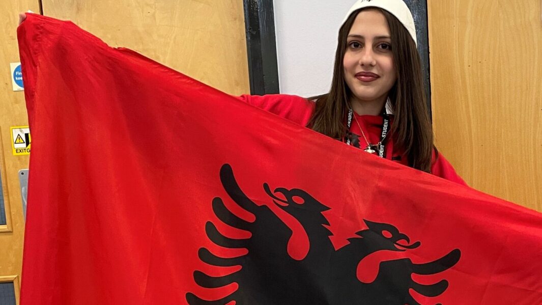 Female student wearing red cultural clothing, holding red and black flag on Carmel Cultural Appreciation Day 2024.
