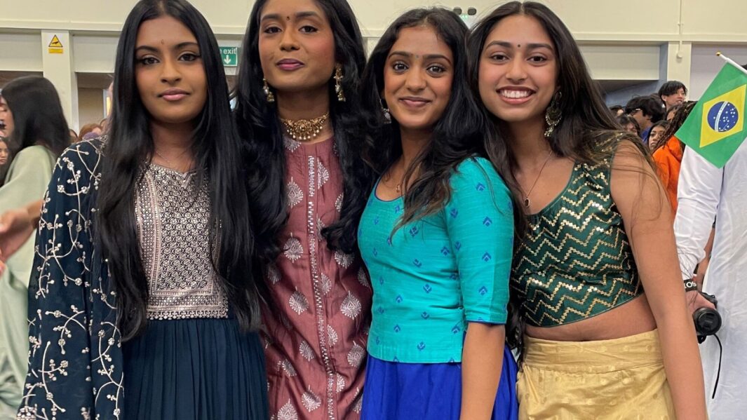 Four female students dressed in cultural Asian clothing pose together as a group.