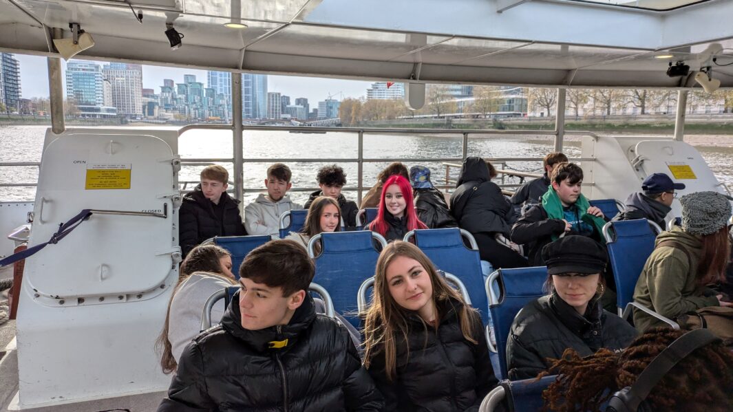 Large group of Carmel College Art, Deisgn and Performing Arts students sitting together on ferry cruising on the river Thames.