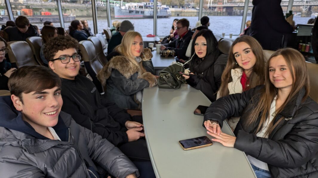 Group of Carmel students smiling whilst sat on ferry.