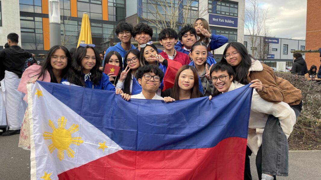 Carmel College's Asian Society pose as a group with Philippine flag.