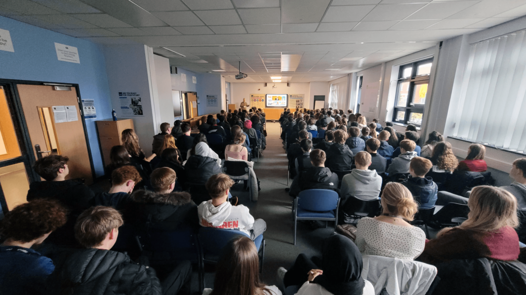 Large classroom packed with students sat listening to lecture from David Laven.