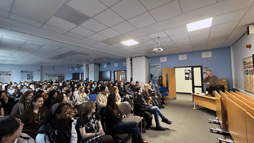 David Laven delivers lecture to packed classroom full of smiling Carmel students.