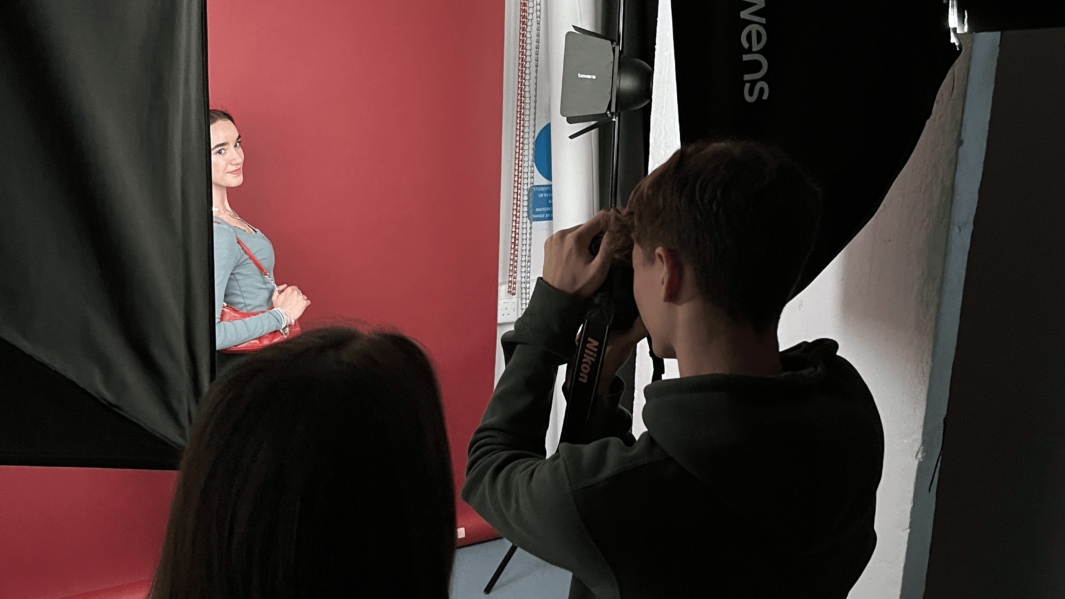 Carmel Art & Design students take pictures of student wearing red accessories in the photography studio.