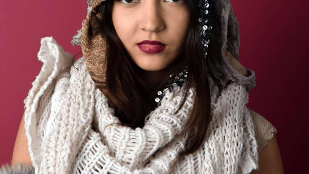 Female student wearing dark red lipstick poses for fashion shoot in front of burgundy backdrop.