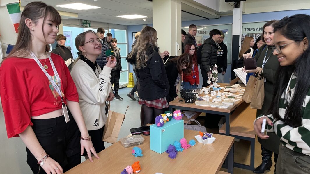 Female student enquires about crochet craft at Carmel College Christmas Market.