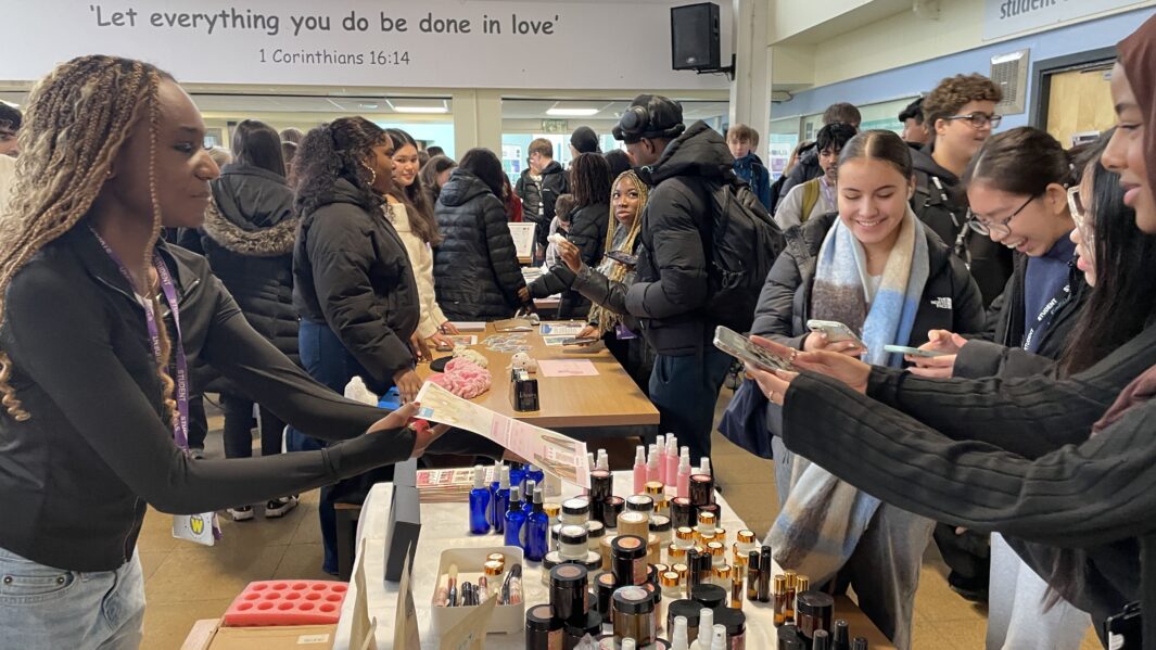 Female student explains bodycare product to inquisitive student buyer.