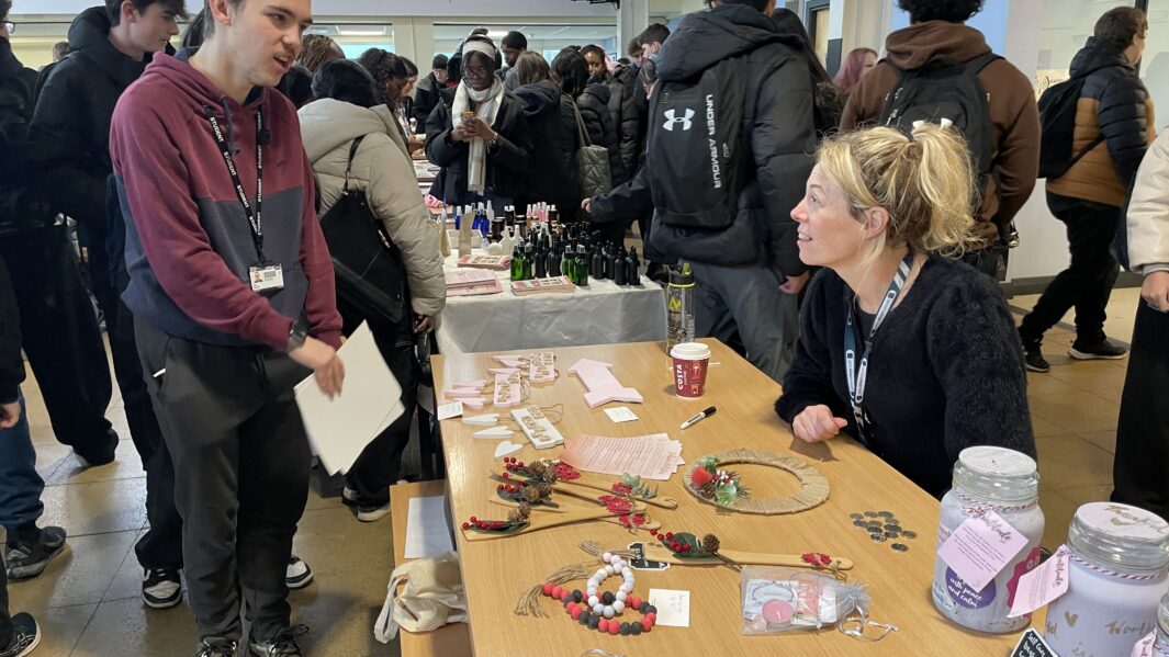 Male students enquires about handmade product at Carmel College's Christmas Markt 2024.