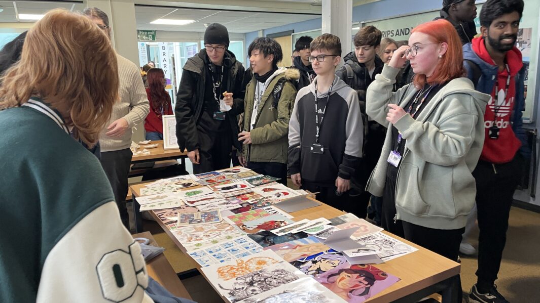 Students crowd round digital art print stall at Christmas Market,