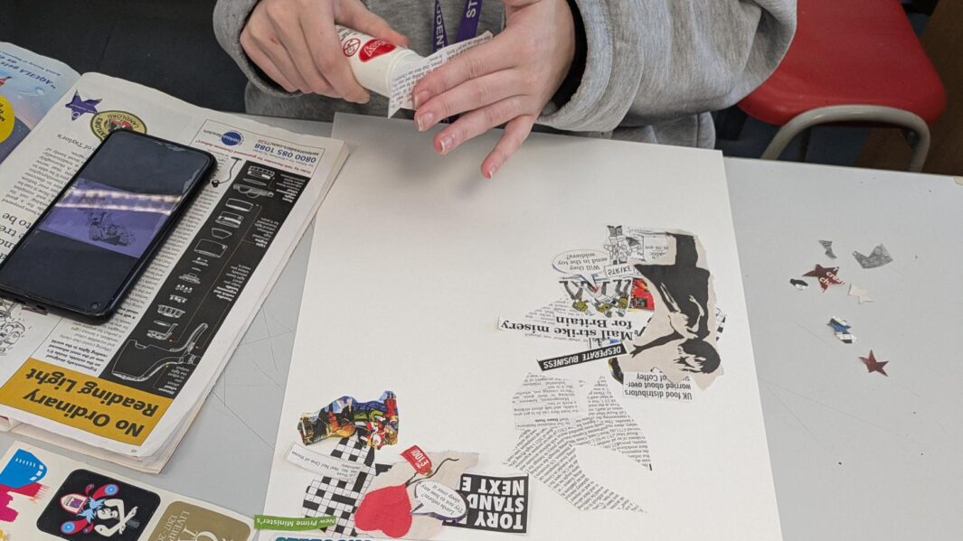 a piece of paper / artwork. student hands using glue to stick together a collage