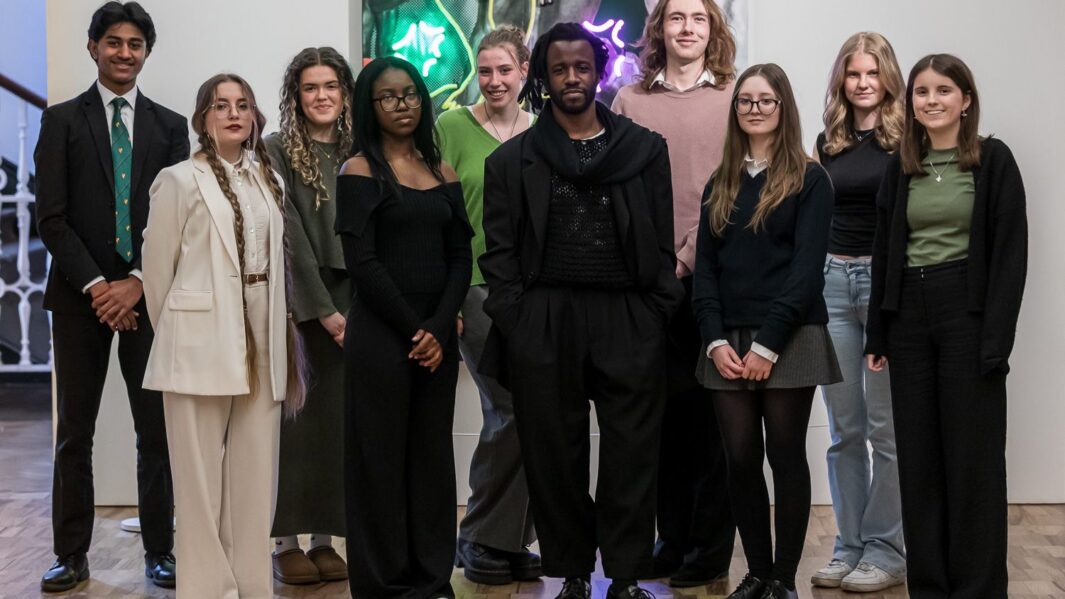 Group photo of a mix of people stood in front of art work