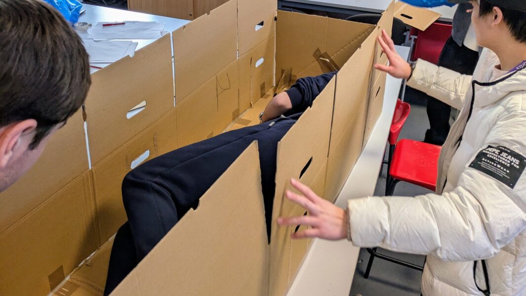 students in class working on architect projects. students in a shelter model cardboard