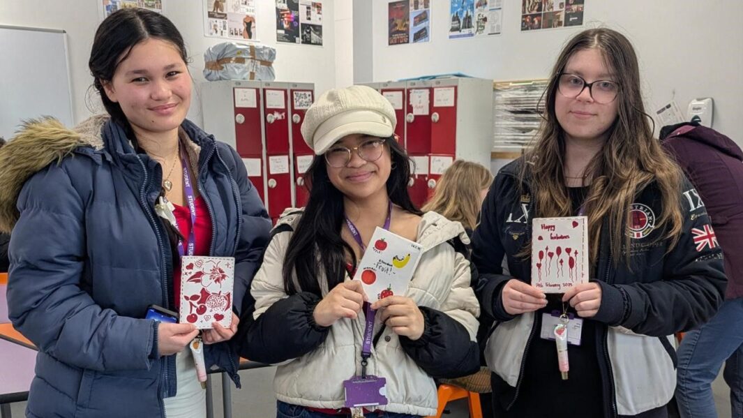 3 students stood holding up zine artwork