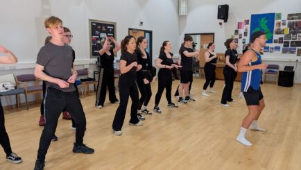 Male performer teaching class of students dance