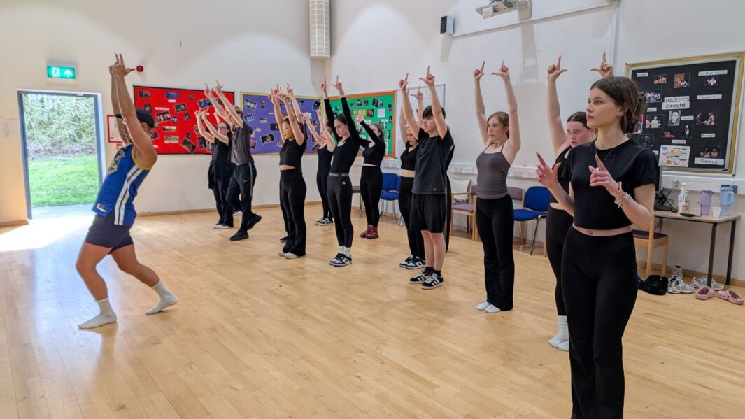 Male performer teaching class of students dance